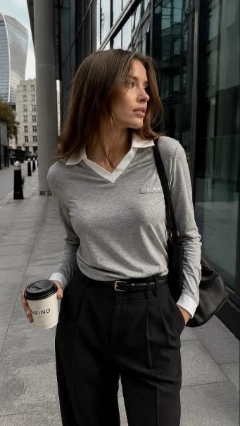 Woman in grey long-sleeve contrast-collar polo top and black tailored trousers walking through a city financial district