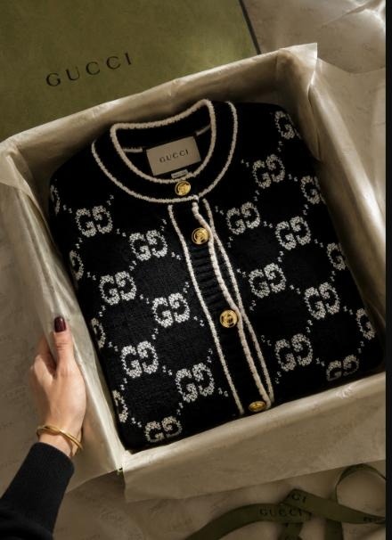Black and ivory Gucci GG monogram wool cardigan with gold buttons, shown being unboxed on tissue paper