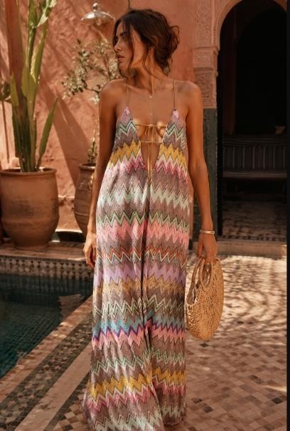 Woman in Missoni multicolour zigzag-knit halter maxi dress standing beside a riad pool, carrying a raffia bag